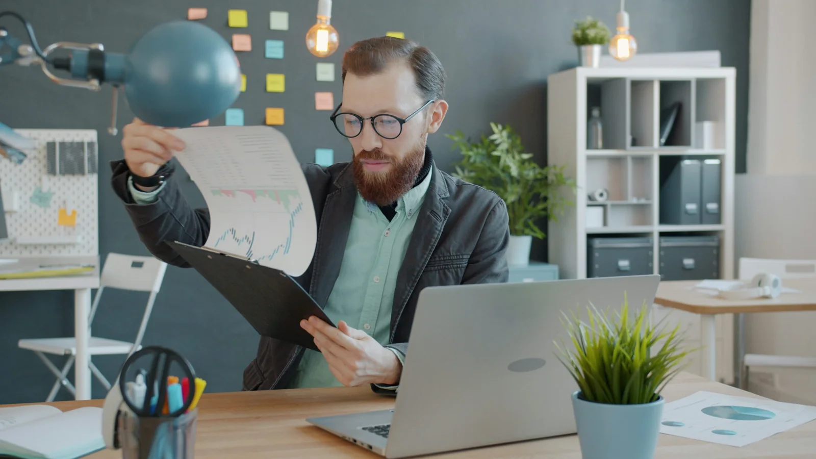 A man reviewing printed documents at an office desk